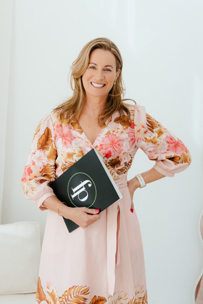 Real Estate agent posing for a portrait while holding a folder with her company logo